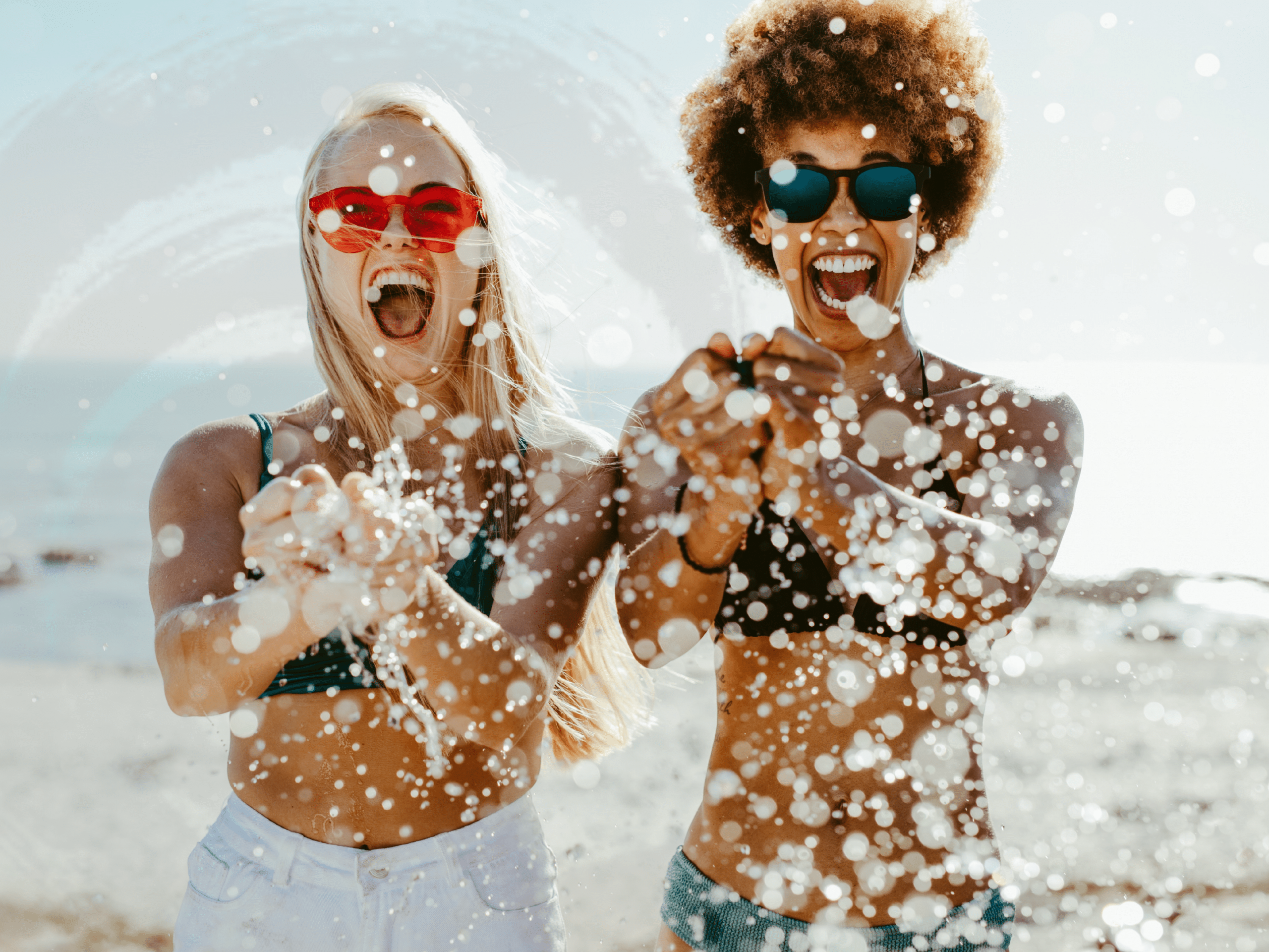 Two friends splashing water at the beach, symbolizing psychiatrists and psychologists