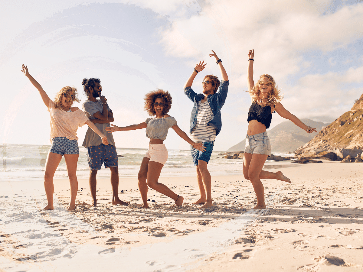 A group of people dancing at the beach, symbolizing how TMS for anxiety is used.