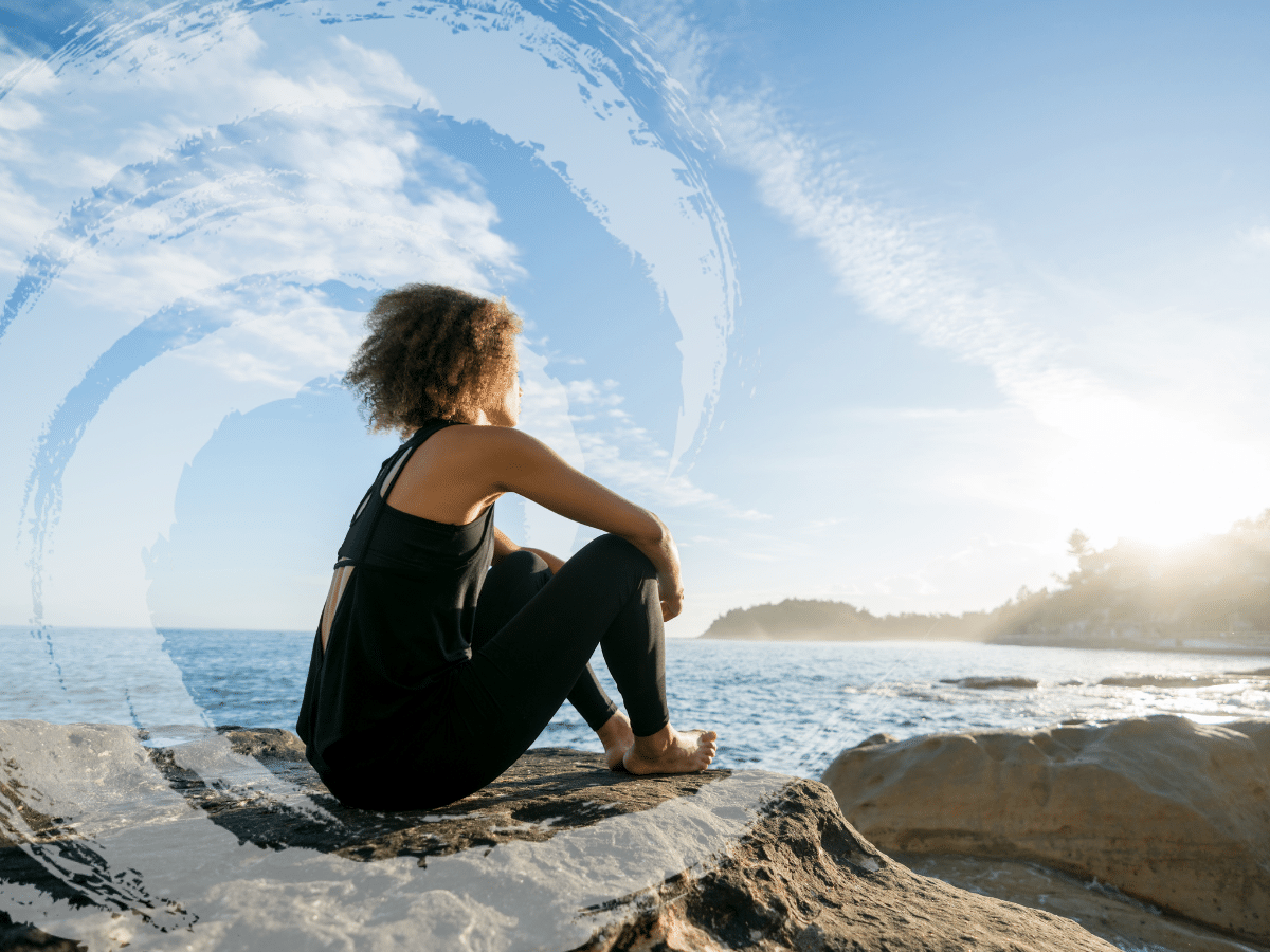 Woman sitting at the beach looking out into the water, symbolizing the journey of addiction therapy