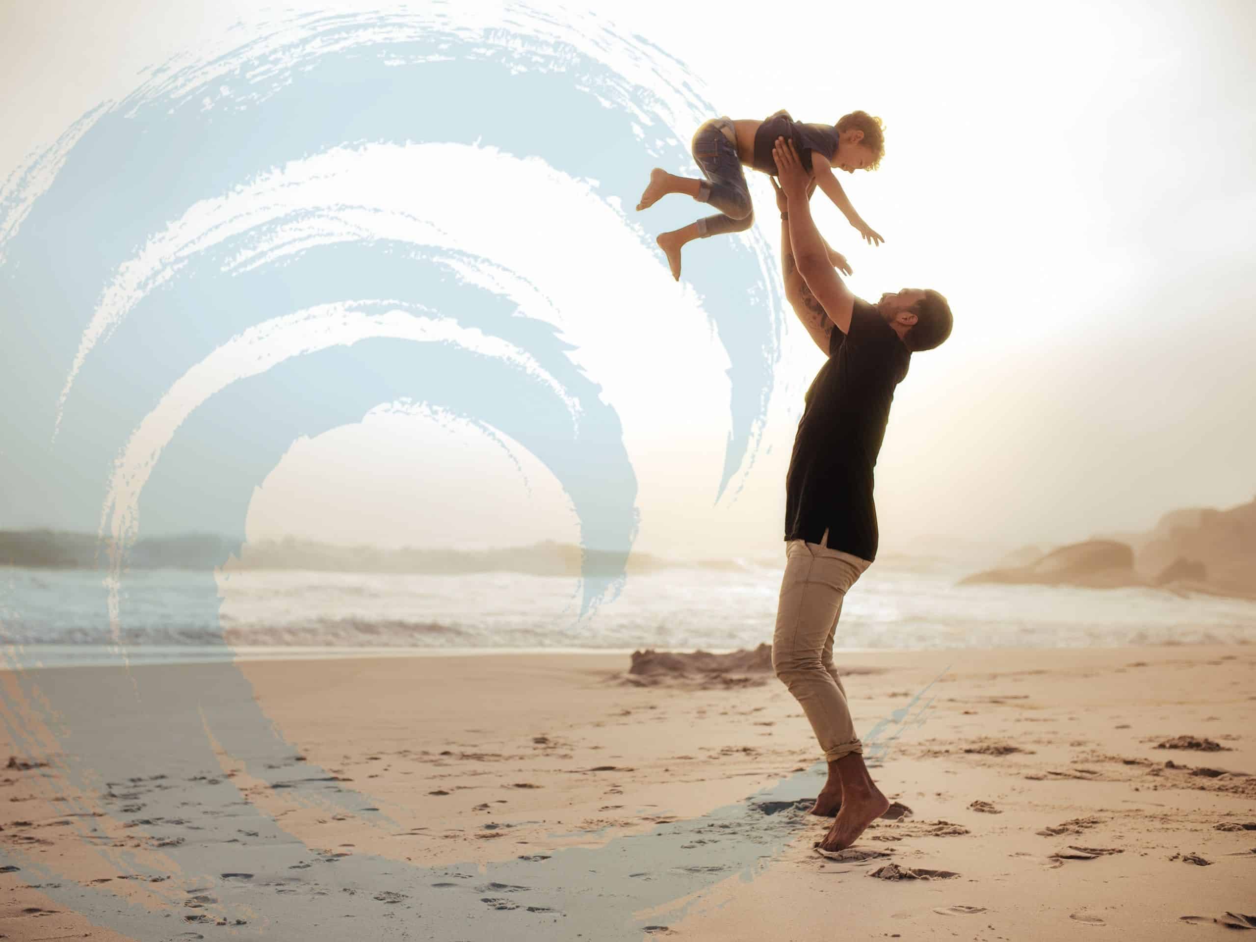 A father tosses his son in the air at the beach, symbolizing the journey of men's mental health.