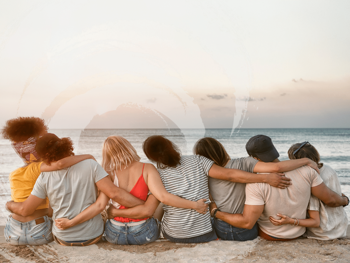 A group of people sitting at the beach with their arms around each other, symbolizing mental health awareness in 2026