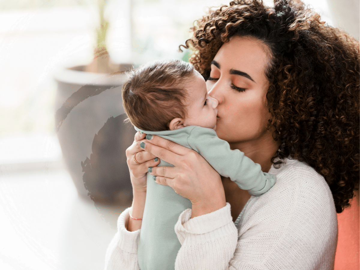 A woman giving her newborn baby a kiss, symbolizing how some mothers struggle with postpartum depression