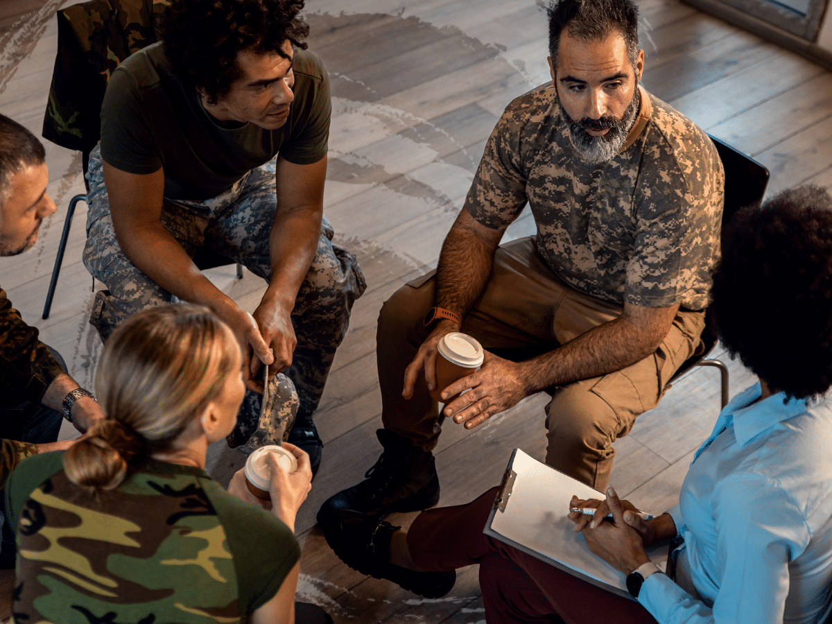 A group of veterans sitting in a circle listening to a therapist, symbolizing PTSD in veterans